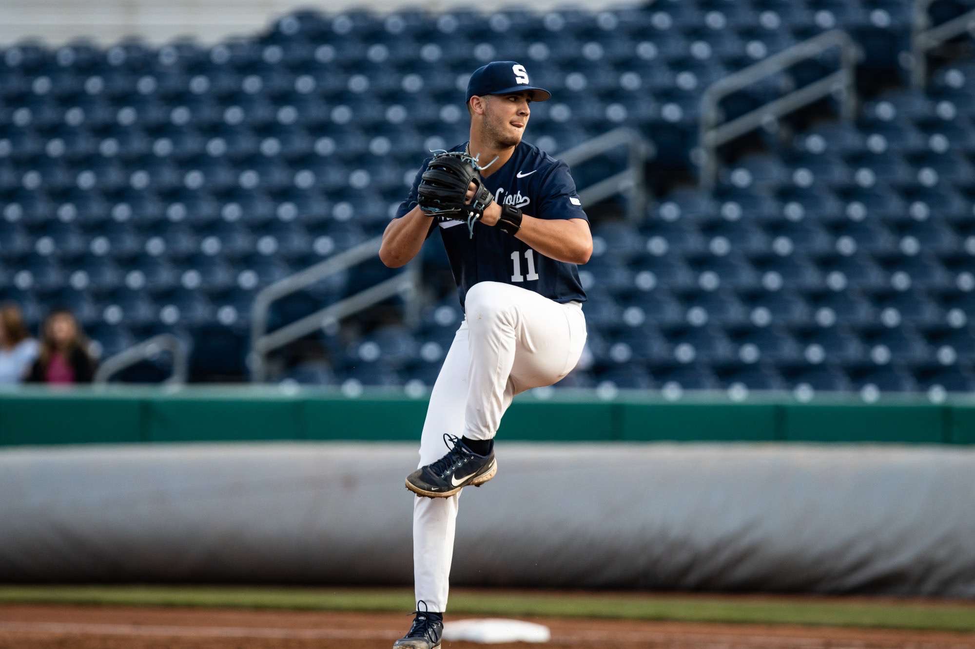 Baseball pitcher in custom team uniform mid-throw on the mound